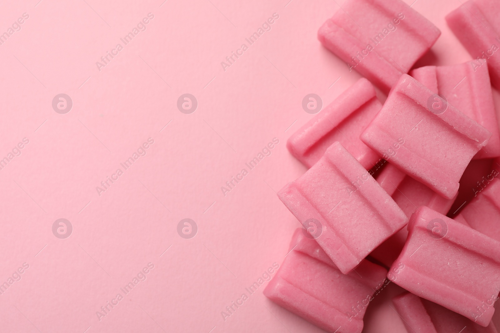 Photo of Tasty chewing gums on pink background, flat lay. Space for text