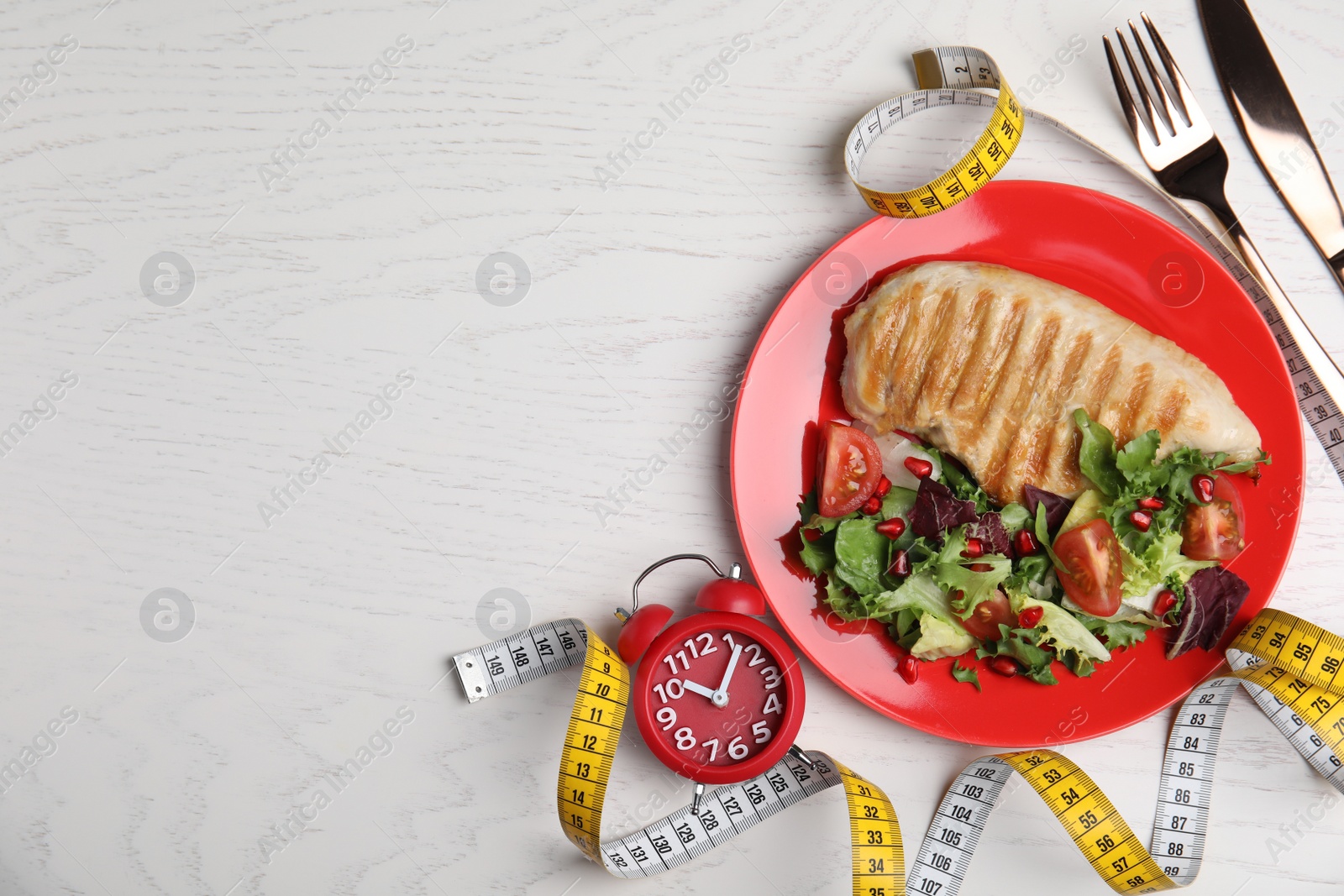 Photo of Flat lay composition with appetizing food and alarm clock on white wooden table, space for text. Nutrition regime