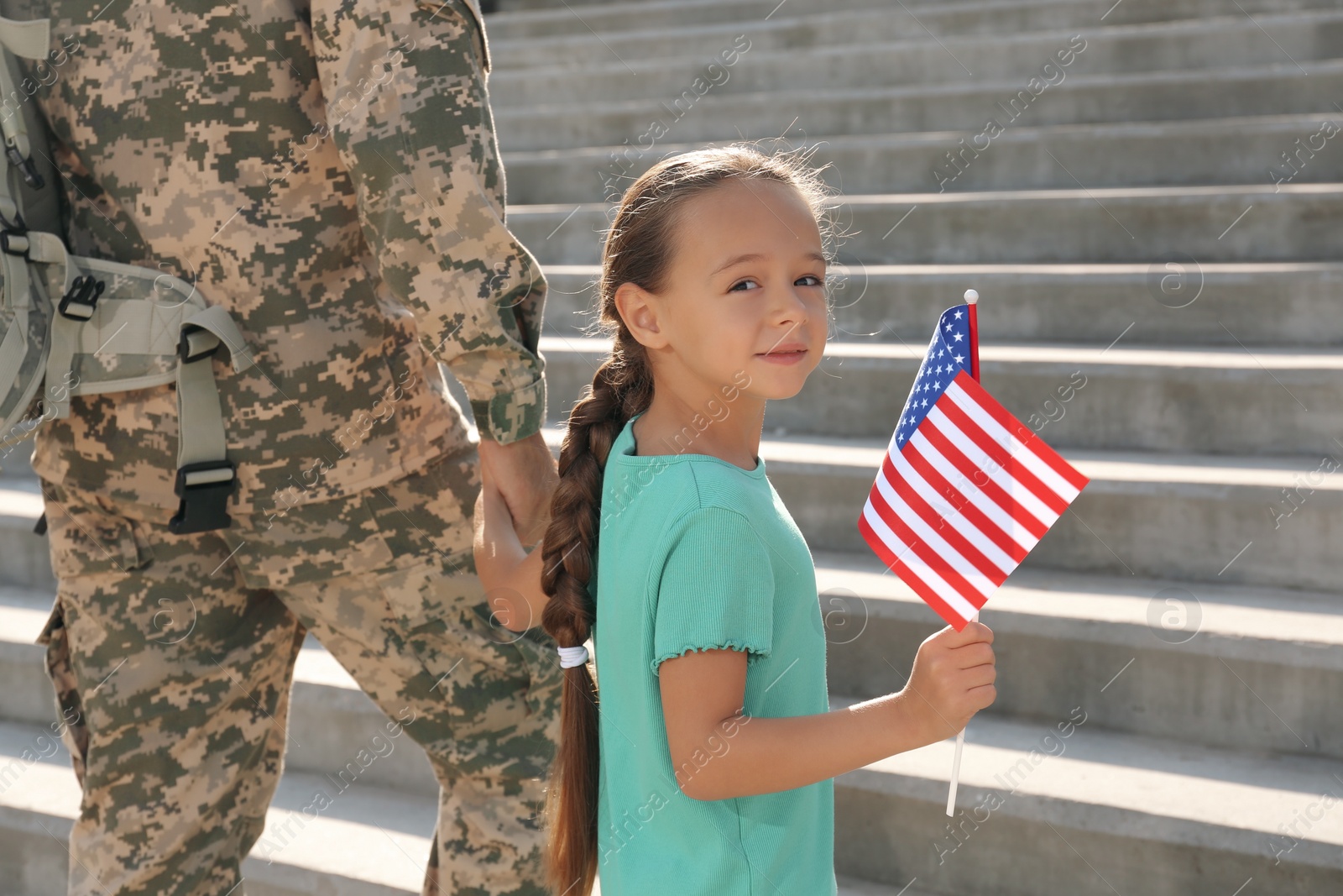 Photo of Soldier and his little daughter with American flag outdoors. Veterans Day in USA