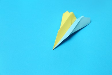 Photo of Colorful paper plane on light blue background, space for text