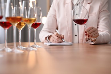 Photo of Sommelier tasting different sorts of wine at table indoors, closeup