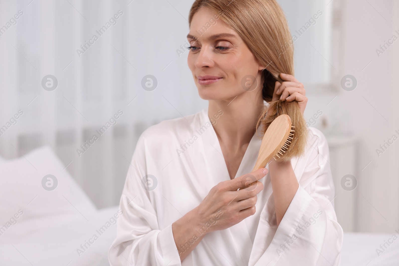 Photo of Beautiful woman brushing her hair in room
