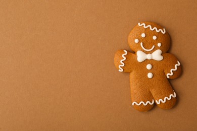 Photo of Christmas human shaped gingerbread cookie on brown background, top view. Space for text