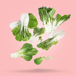 Fresh green pak choy cabbages falling on pale pink background