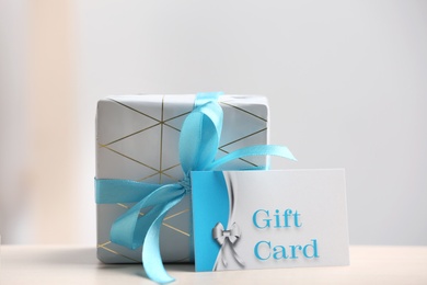 Photo of Gift card and present on table against blurred background