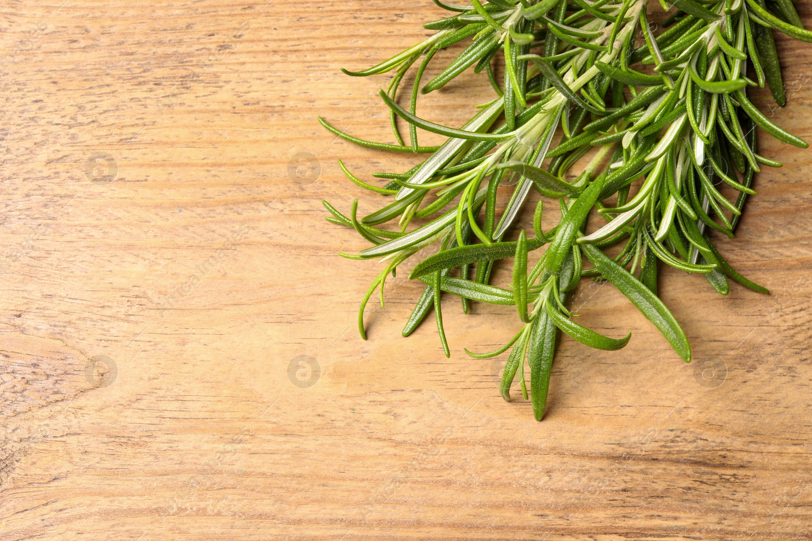 Photo of Fresh green rosemary on wooden table, top view. Space for text