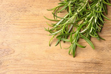 Photo of Fresh green rosemary on wooden table, top view. Space for text