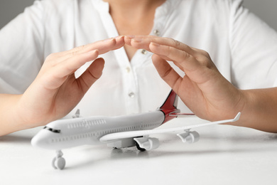 Photo of Woman covering toy plane at white table, closeup. Logistics and wholesale concept