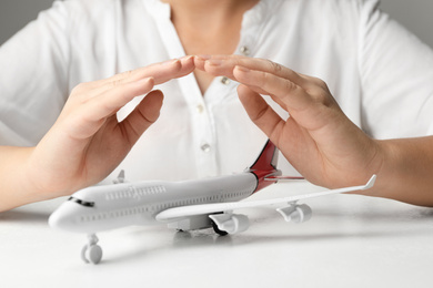 Woman covering toy plane at white table, closeup. Logistics and wholesale concept