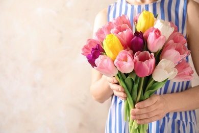 Photo of Girl holding bouquet of beautiful spring tulips on color background, closeup with space for text. International Women's Day