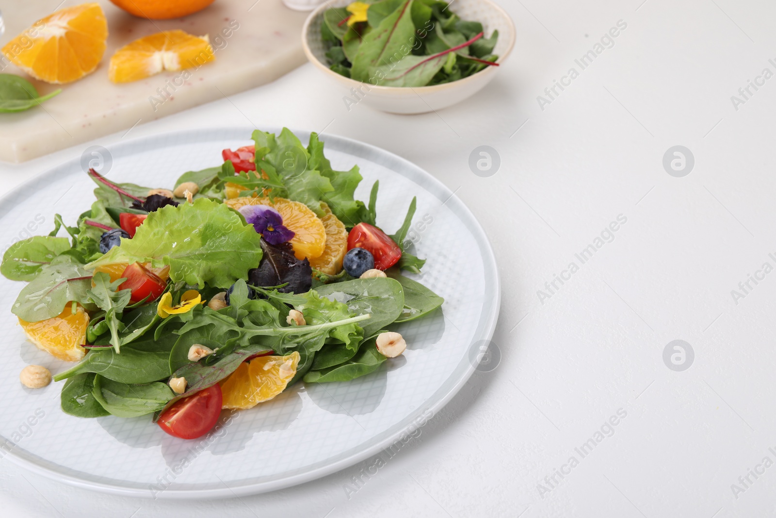 Photo of Delicious salad with tomatoes and orange slices on white table, space for text