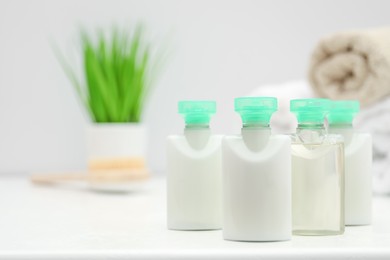 Photo of Mini bottles of cosmetic products on white table against blurred background. Space for text