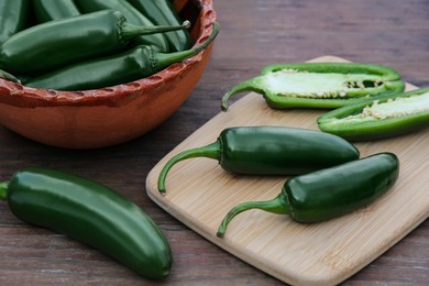 Photo of Whole and cut jalapeno peppers on wooden table, closeup