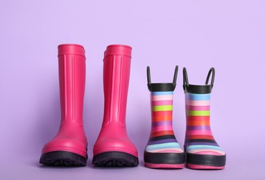 Photo of Two pairs of rubber boots on violet background