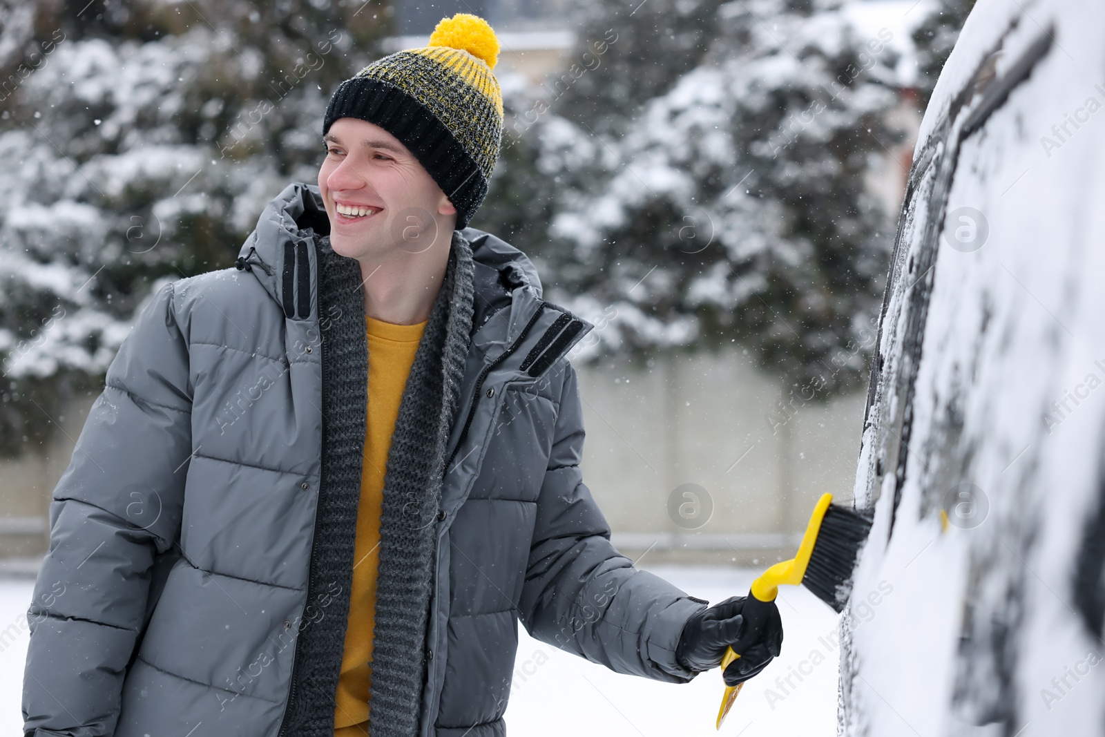 Photo of Man cleaning snow from car window outdoors