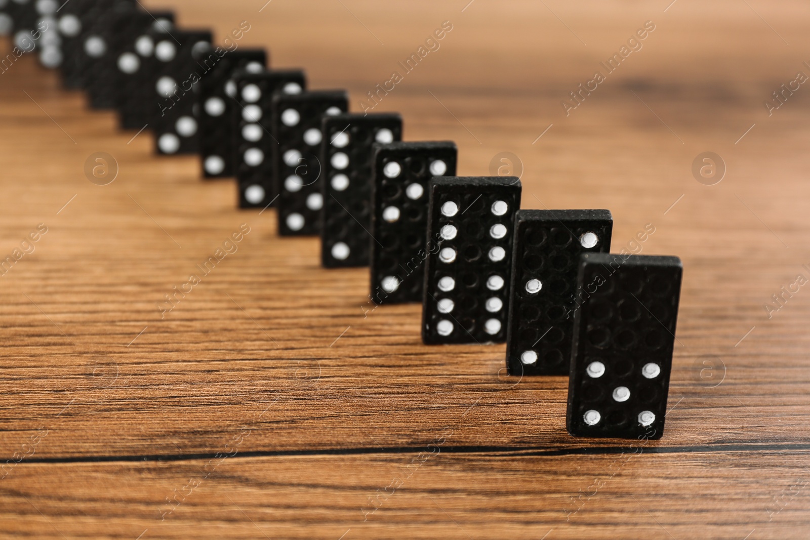 Photo of Black domino tiles with white pips on wooden table