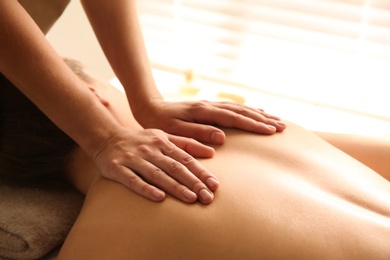 Young woman receiving back massage in spa salon, closeup