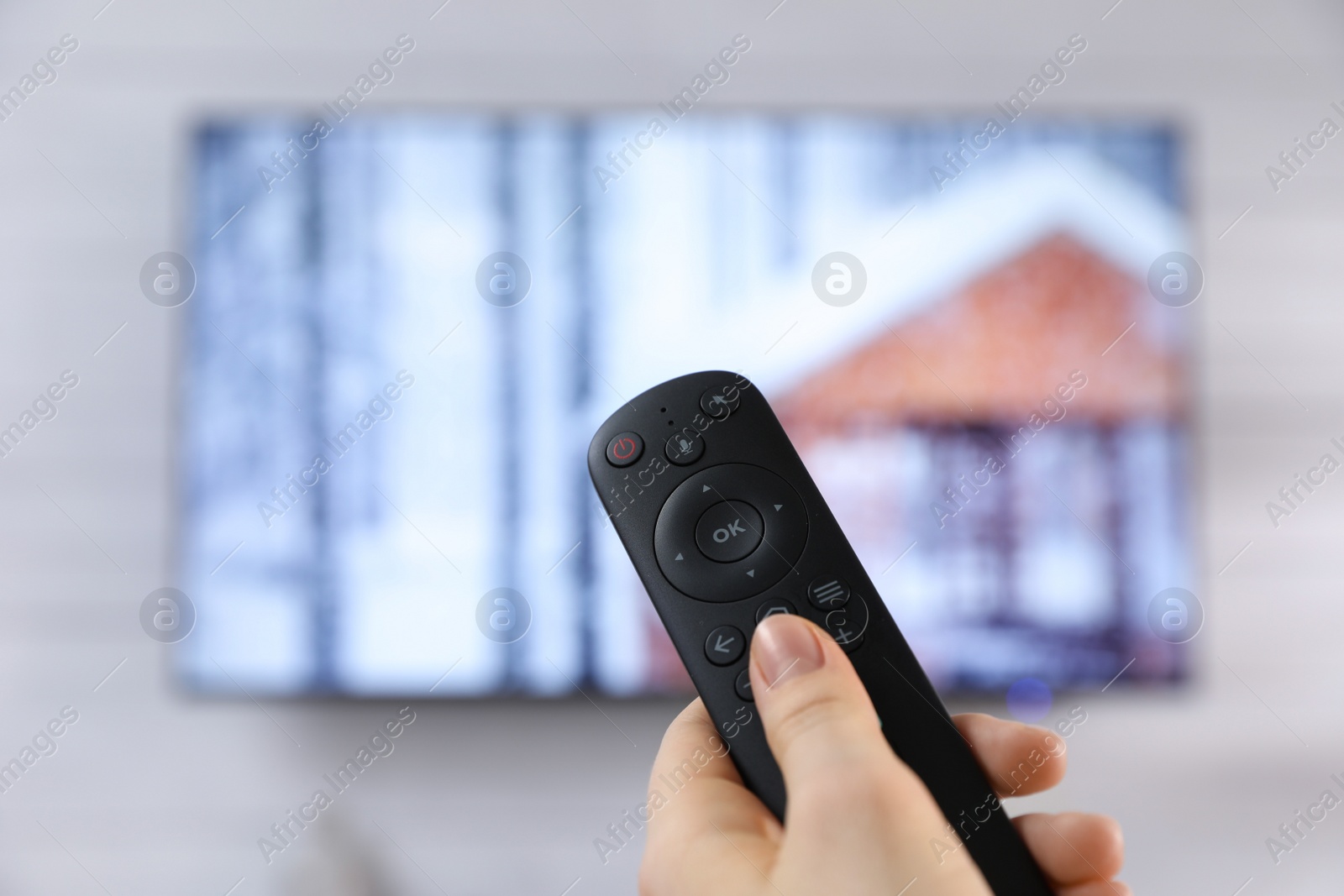 Photo of Woman with remote control watching TV at home, closeup. Space for text