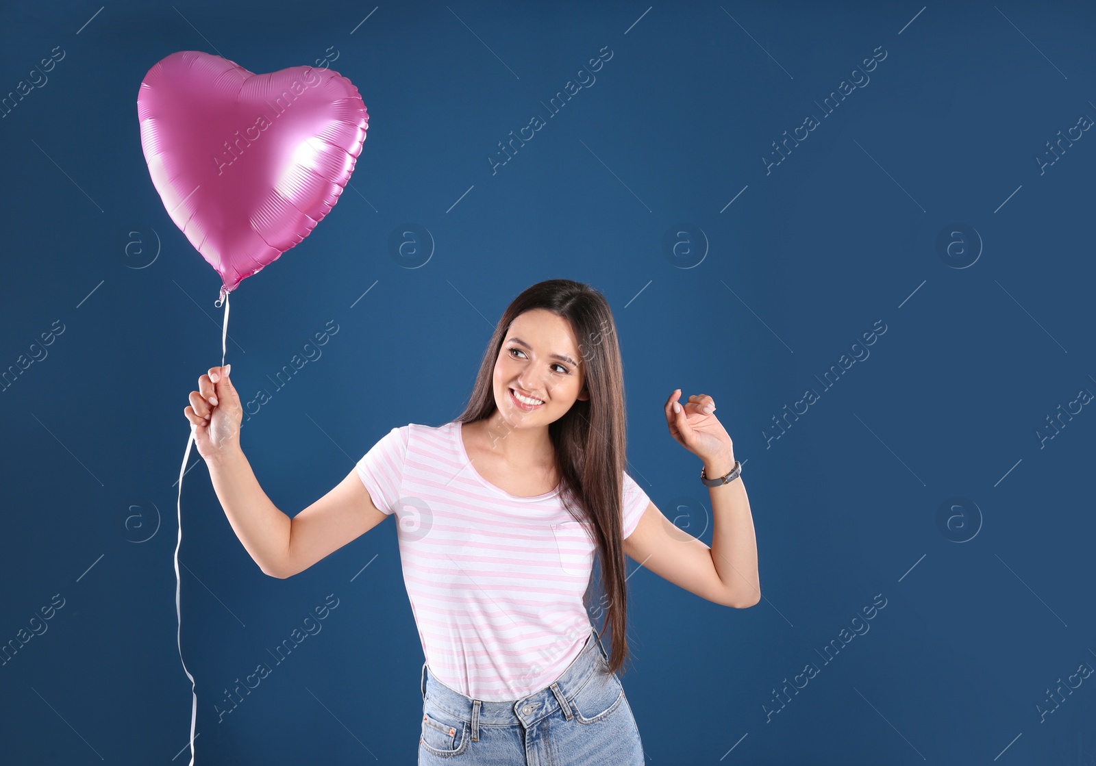 Photo of Portrait of young woman with heart shaped balloon on color background