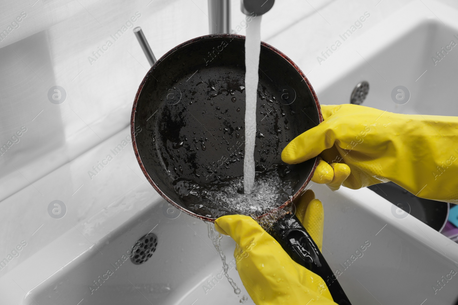 Photo of Woman washing frying pan in kitchen sink, closeup