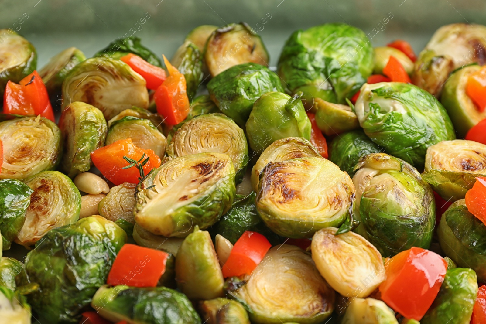 Photo of Delicious roasted brussels sprouts with bell pepper and peanuts as background, closeup