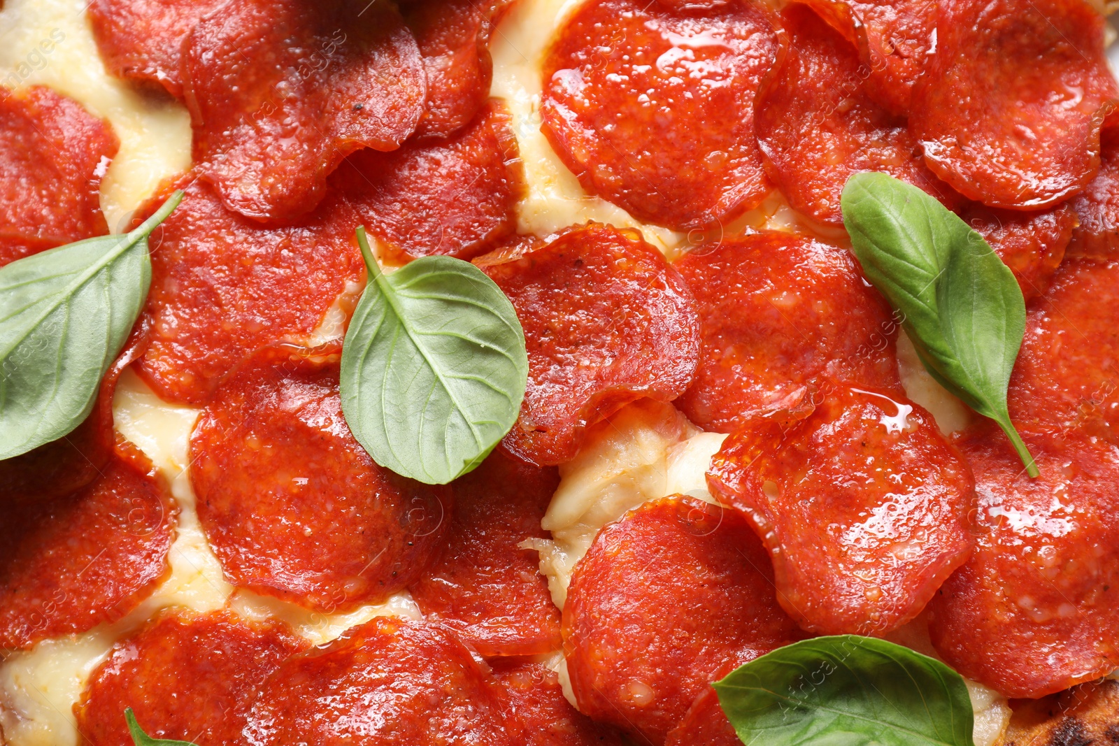 Photo of Tasty pepperoni pizza with basil as background, top view