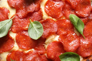 Photo of Tasty pepperoni pizza with basil as background, top view