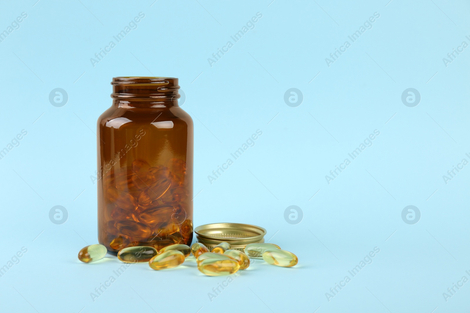 Photo of Jar with vitamin capsules on light blue background, space for text