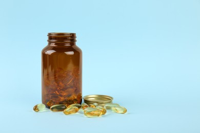 Photo of Jar with vitamin capsules on light blue background, space for text