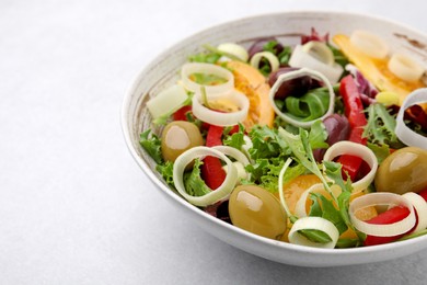 Bowl of tasty salad with leek and olives on light table, closeup. Space for text