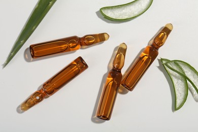 Skincare ampoules and cut aloe leaves on white background, flat lay