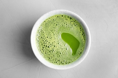 Chawan with fresh matcha tea on grey background, top view