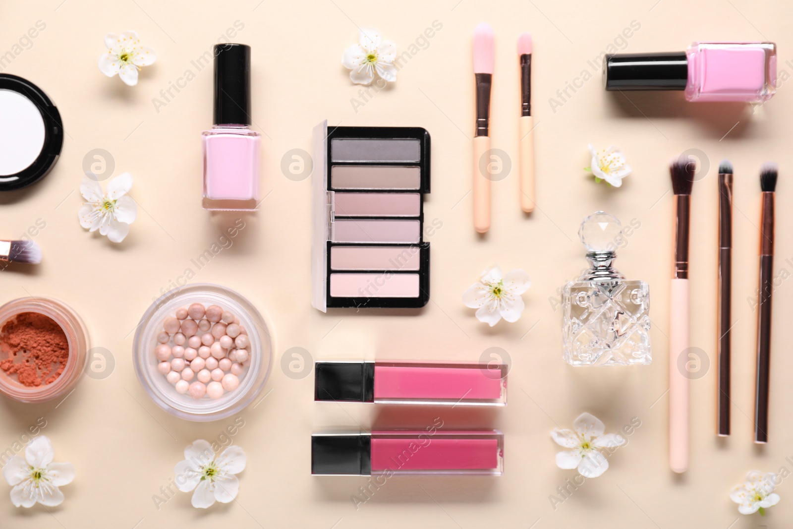 Photo of Flat lay composition with different makeup products and beautiful spring flowers on beige background