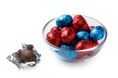 Glass bowl with chocolate eggs wrapped in colorful foil on white background