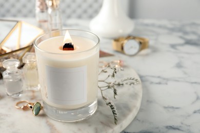 Composition with burning soy candle on white marble table, space for text