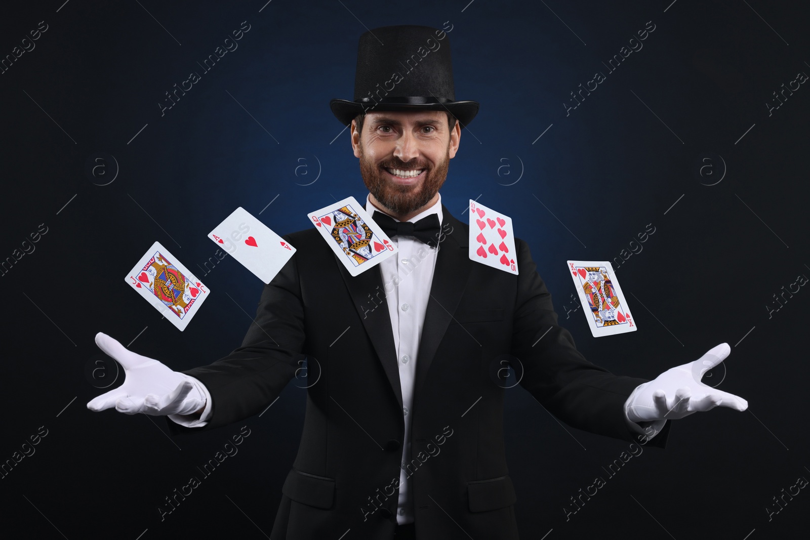 Image of Smiling magician showing trick with cards on dark blue background