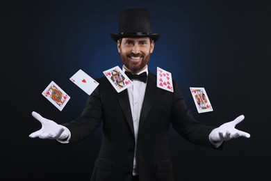 Image of Smiling magician showing trick with cards on dark blue background