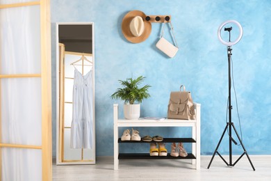 Photo of Stylish room interior with furniture, mirror and ring lamp near light blue wall