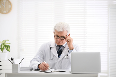 Photo of Senior doctor working at table in office