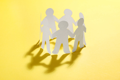 Paper people chain making circle on yellow background. Unity concept