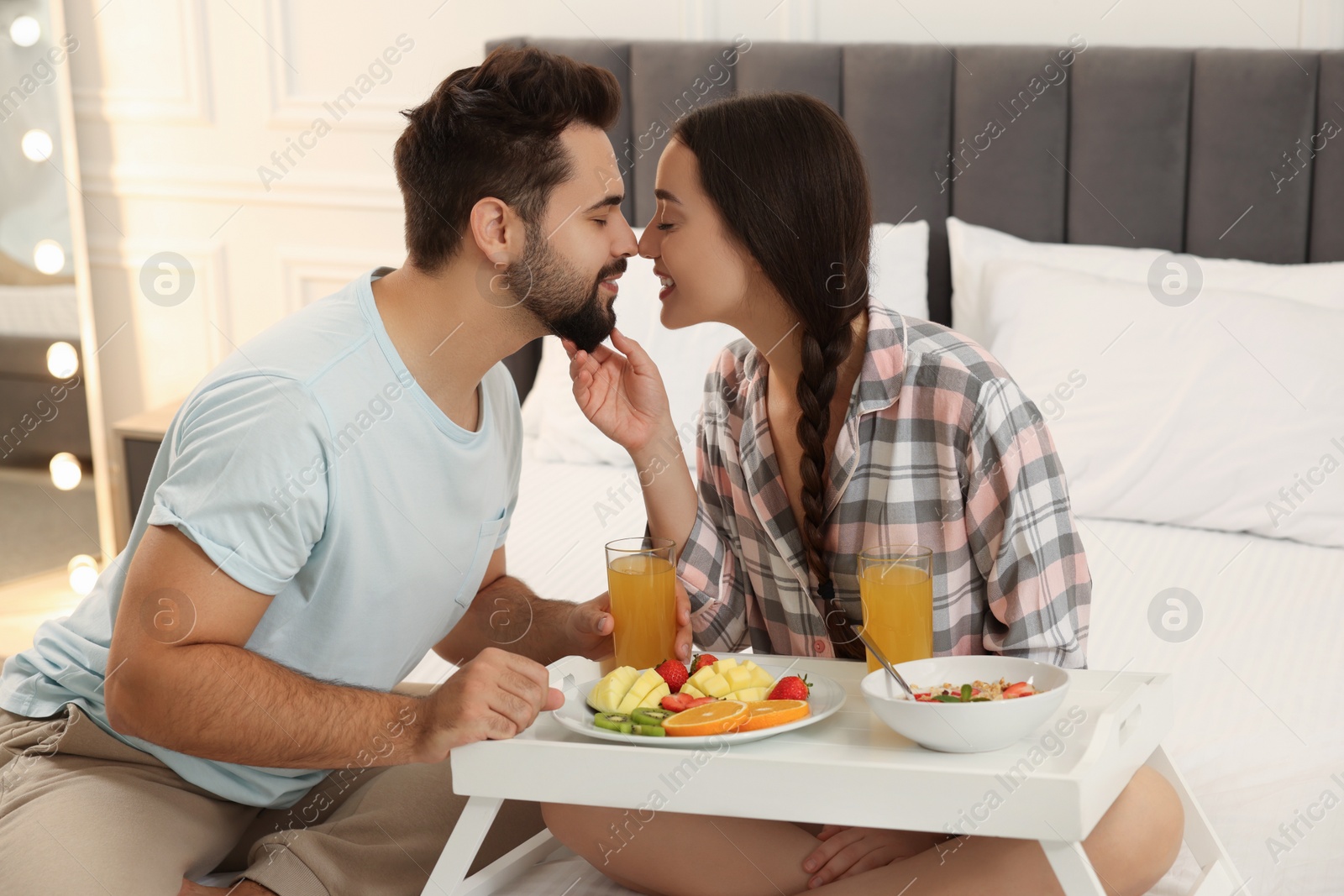 Photo of Happy couple having breakfast on bed at home