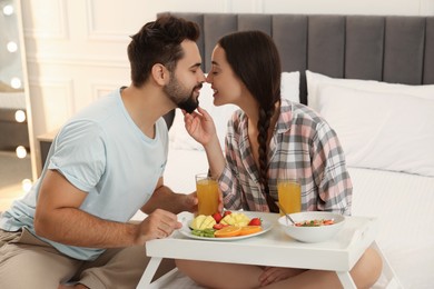Happy couple having breakfast on bed at home