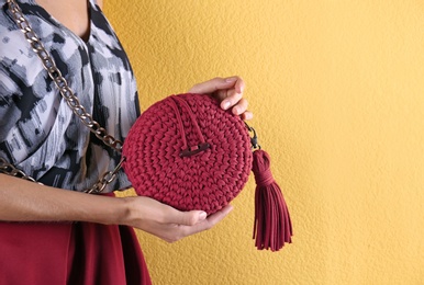 Young woman in stylish outfit with purse on color background, closeup