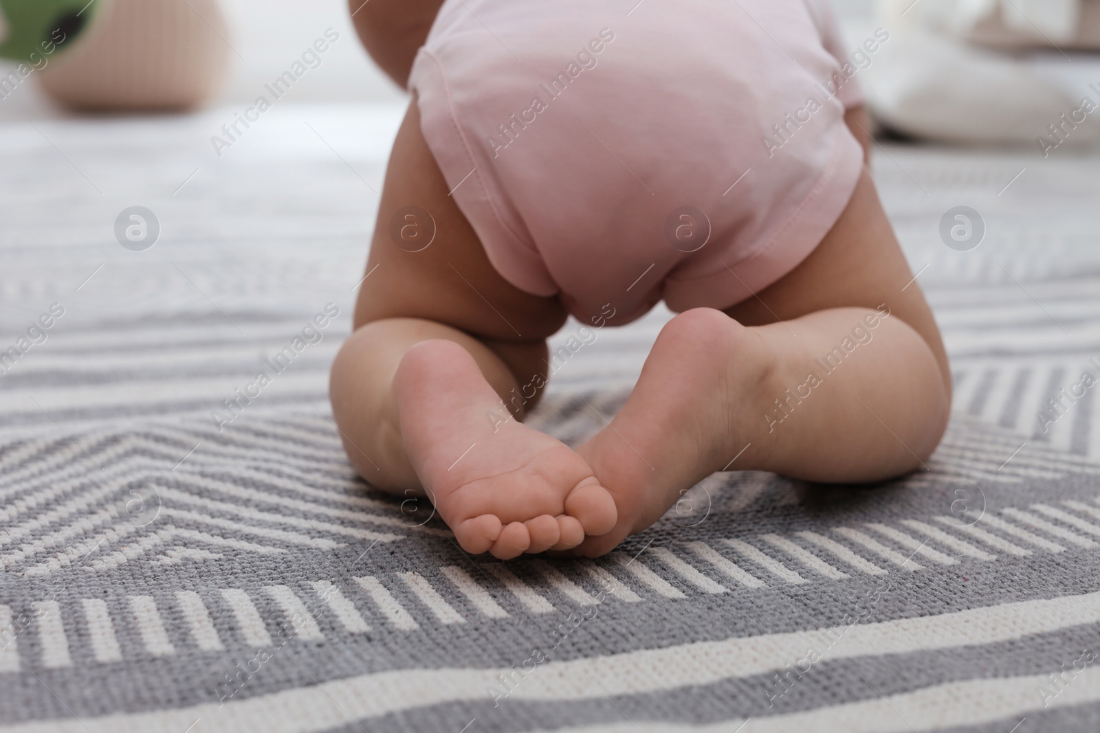 Photo of Baby crawling on floor at home, closeup