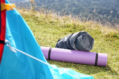 Sleeping bag and mat near camping tent outdoors