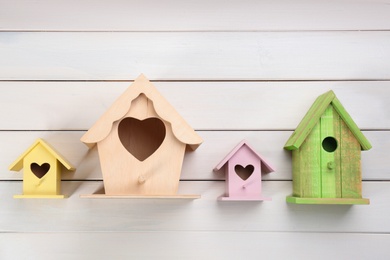 Photo of Collection of handmade bird houses on white wooden background, flat lay