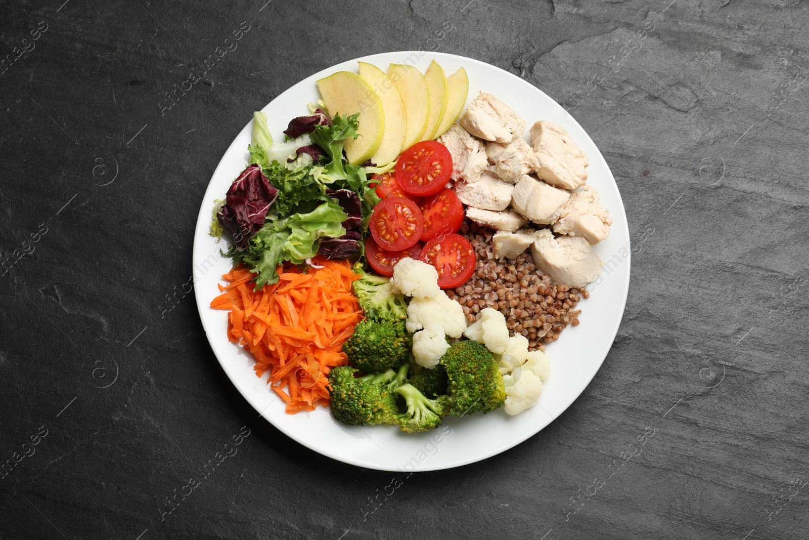 Photo of Balanced diet and healthy foods. Plate with different delicious products on black table, top view