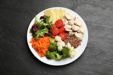 Photo of Balanced diet and healthy foods. Plate with different delicious products on black table, top view