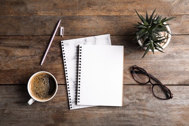 Photo of Flat lay composition with notebooks, coffee and plant on wooden background