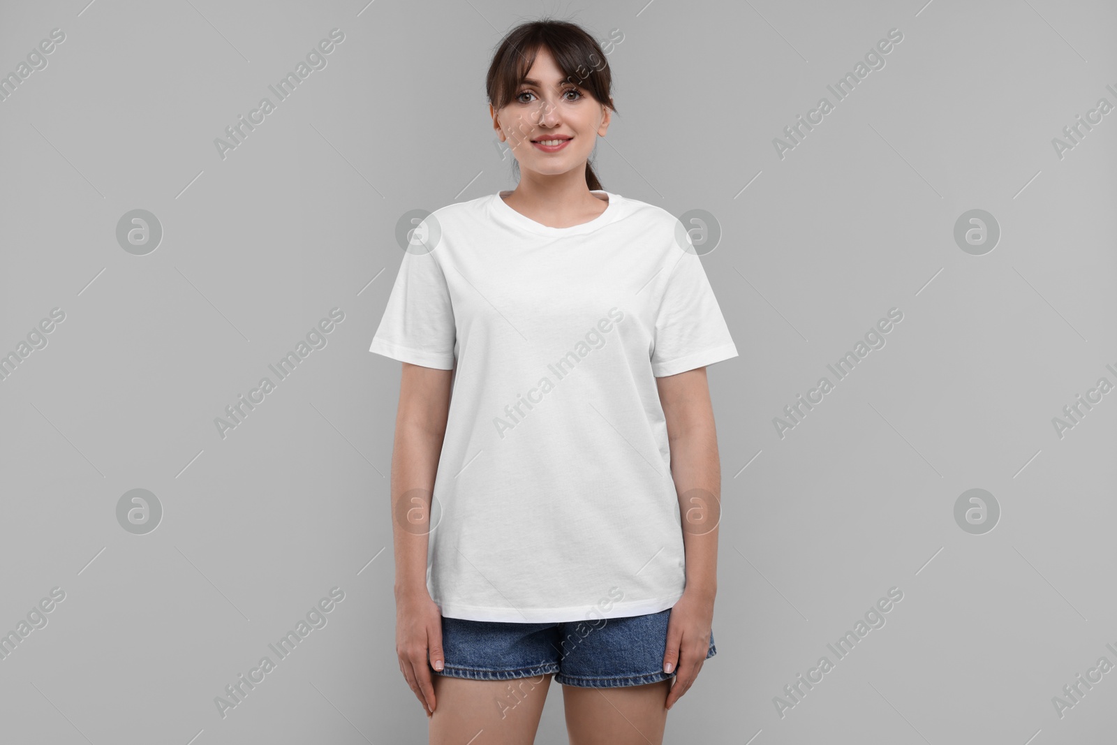 Photo of Smiling woman in white t-shirt on grey background